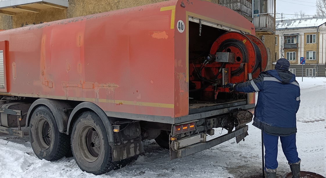 Каналопромывочная машина и работник прочищают засор в канализационной системе в Муравленко
